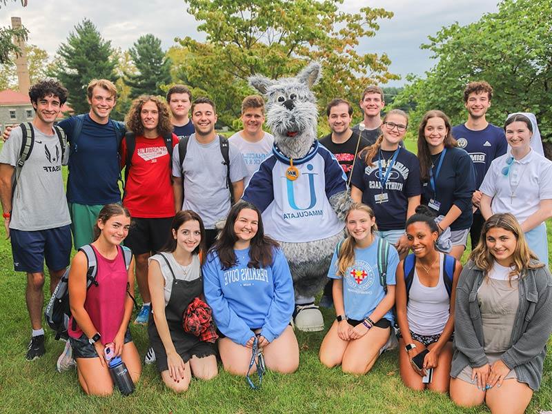 Group of college students gathered around a costumed mascot